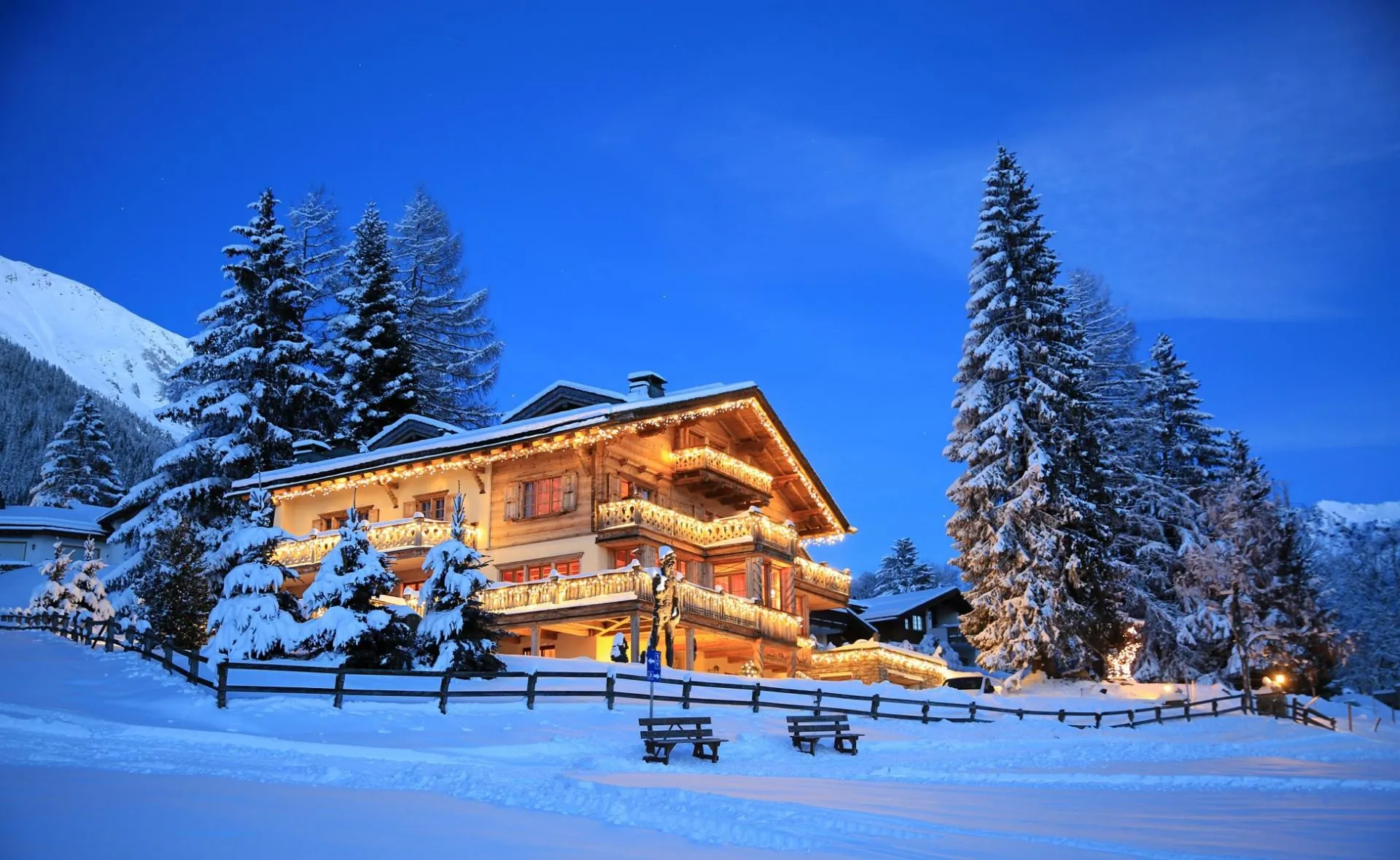Chalet Kalem in Klosters, lit up at dusk in deep snow