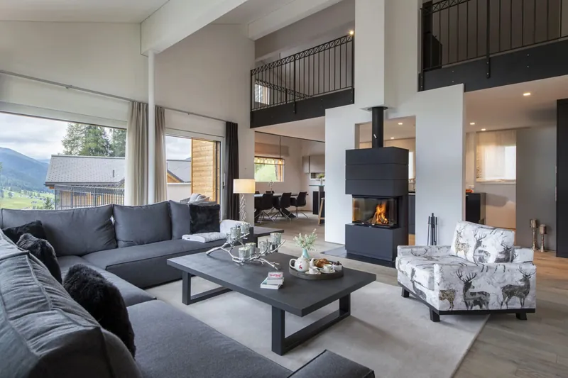 Living room of Chalet Kyla in Davos, with a suspended fireplace and mountain windows